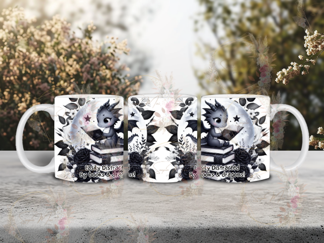 White ceramic coffee mug with an 'Easily Distracted by Books & Dragons' sublimation print, featuring a black and white dragon, book stack, floral elements, and moon, great for your morning brew.